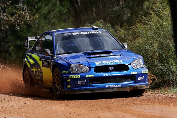 Blue Subaru WRT rally car on dirt course